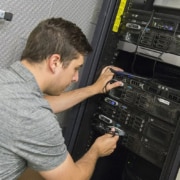 technicien informatique travaillant dans une armoire de brassage de cable réseau