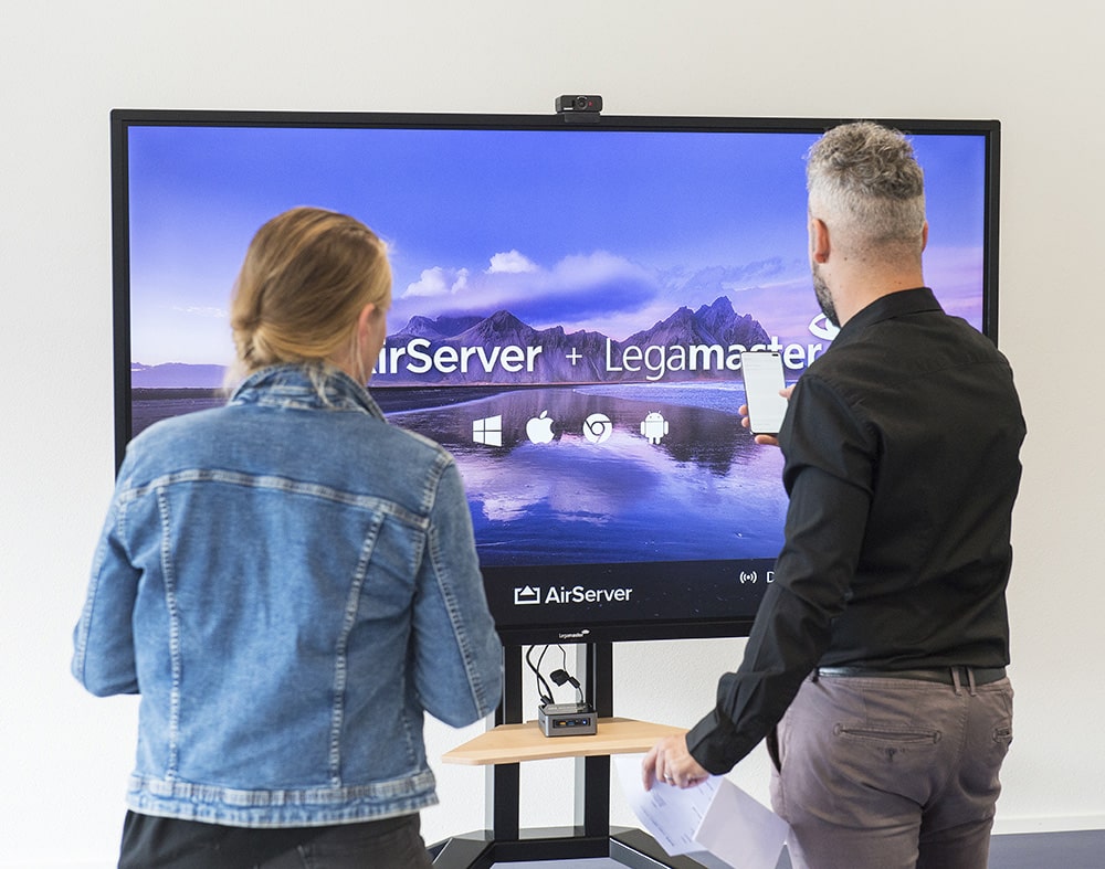 Une femme et un homme devant un grand écran interactifs